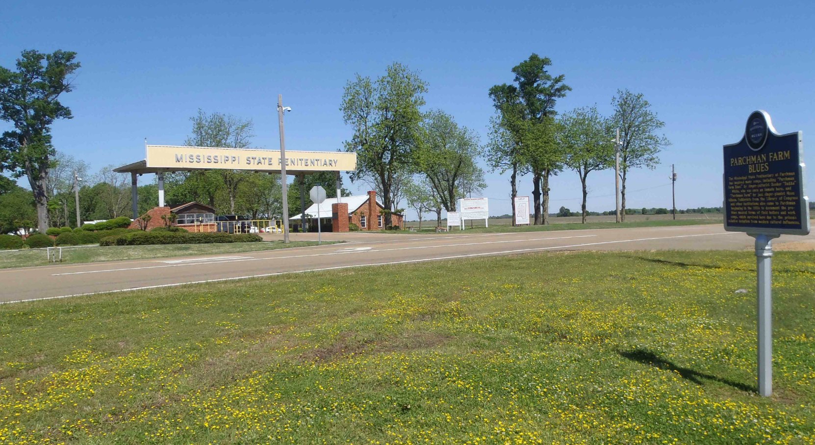 Miississippi Blues Trail marker for Parchman Farm Blues and the main gate of the Mississippi State Penitentiary