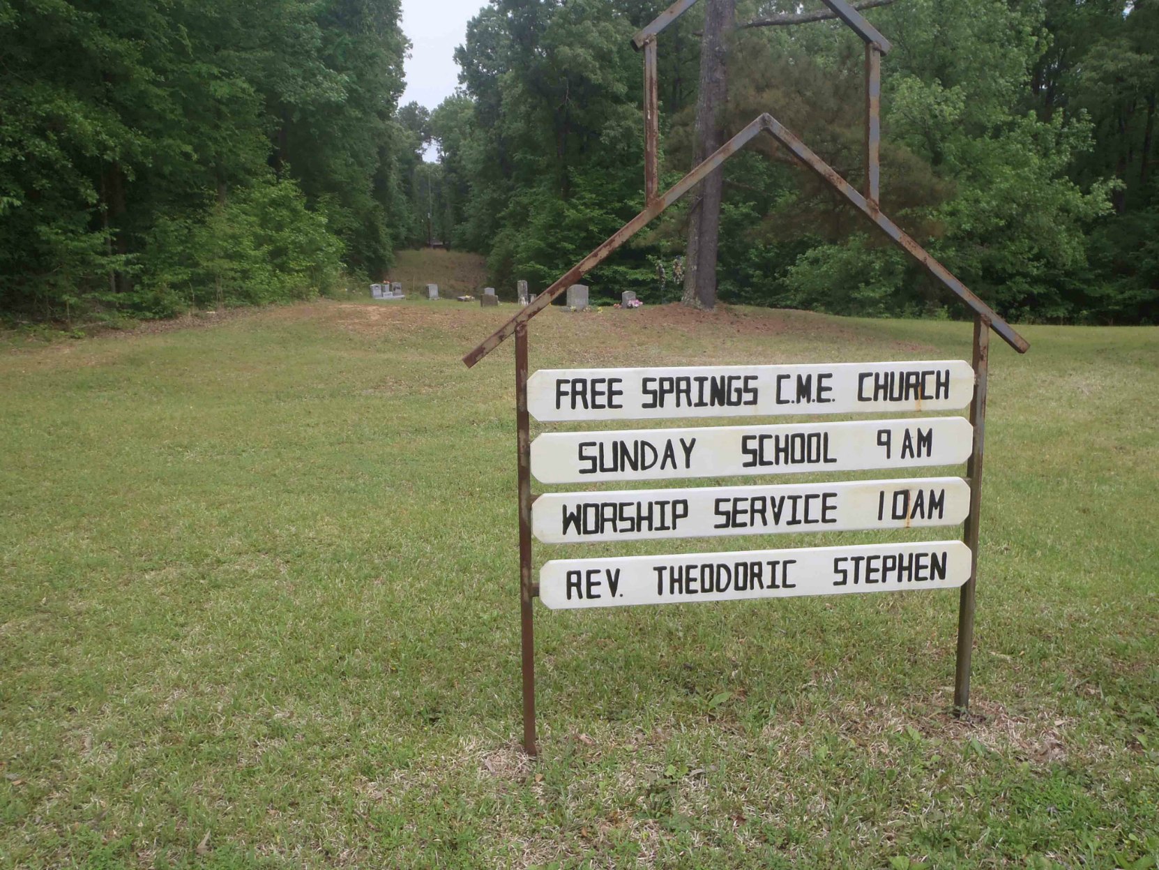 Free Springs C.M.E. Church sign as it appears from the road. R.L. Burnside's grave is in the cemetery visible behind the sign.